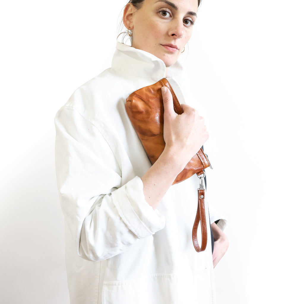 Close-up of model holding zip pouch medium in rodeo saddle and saddle. 